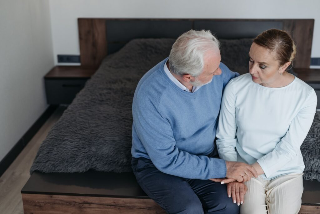 Two people sitting together holding hands in a quiet moment of support