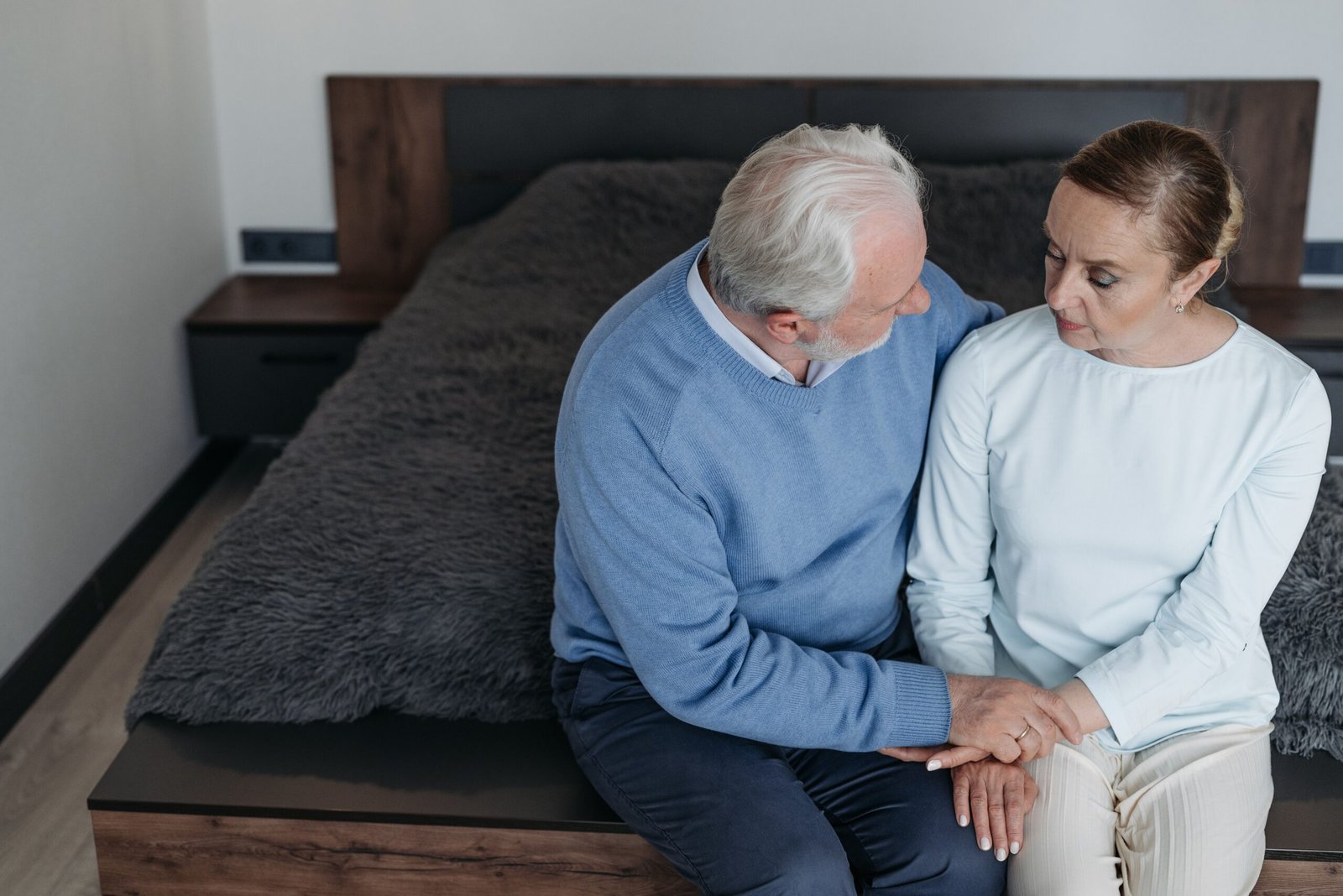 Two people sitting together holding hands in a quiet moment of support